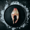 Raw fresh fish steak displayed on a black plate over crushed ice — premium New Zealand seafood available from Harbour Fish or added to your fresh fish delivery.