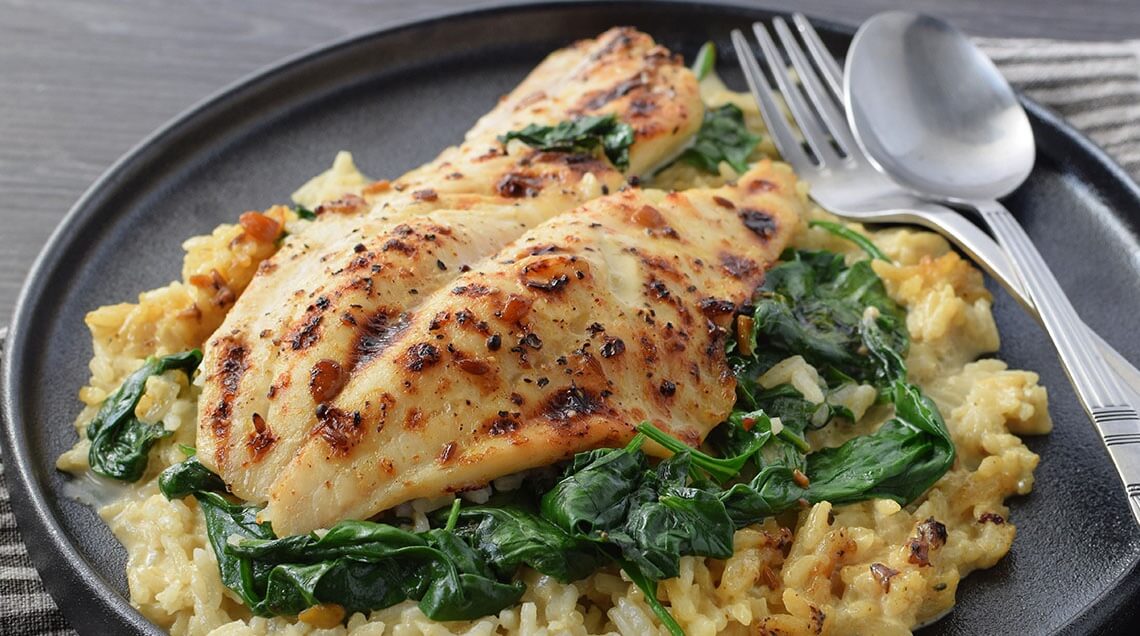 Oven-baked fish fillet served on coconut tamarind rice with spinach in a creamy Florentine seafood dish.